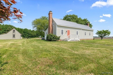View of side of property with a chimney, a lawn, a