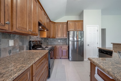 Spacious kitchen featuring rich wooden cabinetry and granite countertops. 