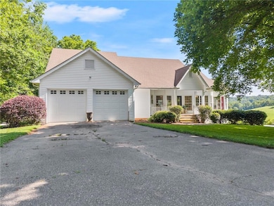 View of front of house featuring covered porch, an attached garage, asphalt driveway, a front yard, and a shingled roof
