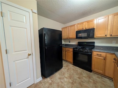 Kitchen with dark countertops, a textured ceiling,