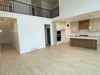 Kitchen with a high ceiling, recessed lighting, a center island with sink, light wood-style floors, and wall oven