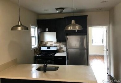 Kitchen with dark cabinets, stainless steel appliances, a peninsula, and light countertops