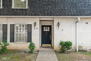 Property entrance with a shingled roof, brick siding, and mansard roof