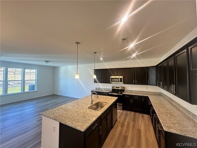 Kitchen with a center island with sink, light wood-type flooring, sink, decorative light fixtures, and appliances with stainless steel finishes