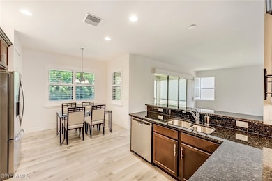 Kitchen with stainless steel appliances, recessed lighting, healthy amount of natural light, light wood-style floors, and a chandelier