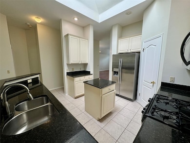 Kitchen featuring stainless steel fridge, recessed lighting, light tile patterned flooring, a kitchen island, and black range with gas stovetop