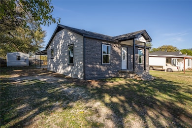 View of front facade featuring a front lawn, an outdoor structure, and brick siding