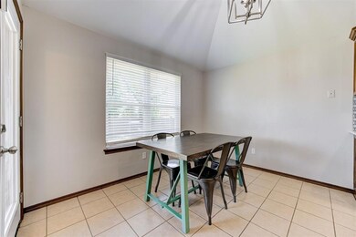 Dining room with vaulted ceiling, a chandelier, light tile patterned floors, and baseboards