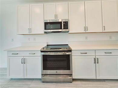 Kitchen featuring appliances with stainless steel finishes, light countertops, and white cabinets