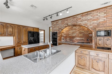 Kitchen with a sink, visible vents, black applianc