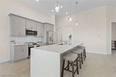 Kitchen featuring decorative light fixtures, stainless steel appliances, backsplash, a center island with sink, and sink