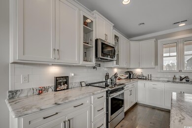 Kitchen featuring stainless steel appliances, white cabinetry, glass insert cabinets, tasteful backsplash, and crown molding
