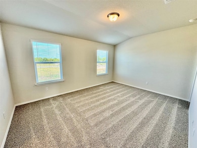 Carpeted spare room with vaulted ceiling and baseboards