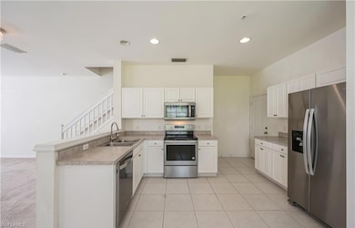 Kitchen with stainless steel appliances, a peninsula, recessed lighting, white cabinetry, and light tile patterned flooring