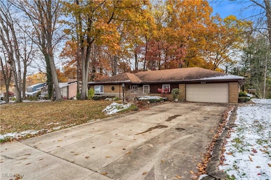 Single story home with driveway, brick siding, and an attached garage