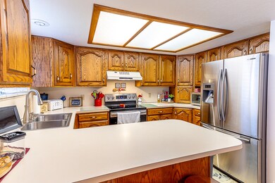 Kitchen with appliances with stainless steel finishes, brown cabinetry, and light countertops