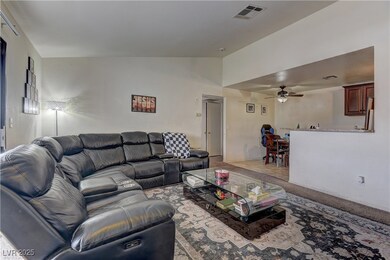 Living room with lofted ceiling, visible vents, and ceiling fan