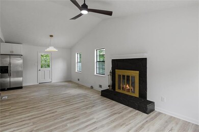 Unfurnished living room featuring light wood-style flooring, a ceiling fan, a premium fireplace, baseboards, and high vaulted ceiling