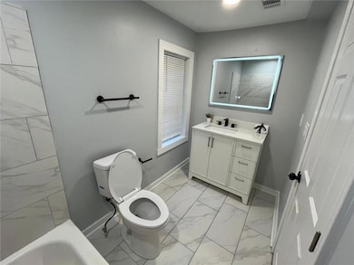 Bathroom featuring marble finish floor, a shower, toilet, and baseboards