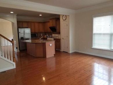 Kitchen with appliances with stainless steel finishes, a kitchen island with sink, dark stone counters, ornamental molding, and ventilation hood