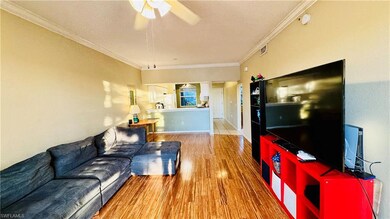 Living area featuring crown molding, light wood-style floors, a textured ceiling, and ceiling fan