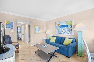Living area with crown molding, light tile floorin