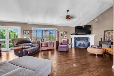 Living area with vaulted ceiling, wood finished floors, a fireplace, and ceiling fan