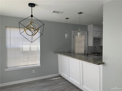 Kitchen featuring light wood-style floors, white cabinetry, hanging light fixtures, backsplash, and a chandelier