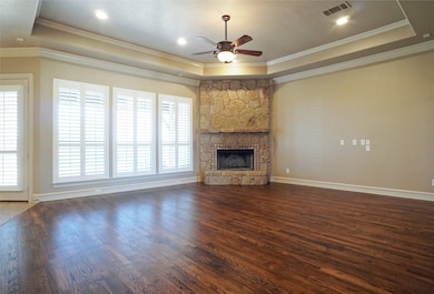 Living room with a wood burning  
 fireplace with optional propane gas connection, ceiling fan, oakwood finished floor and a raised ceiling
