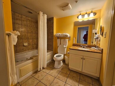 Bathroom featuring a combined bath / shower with jetted tub, vanity, and light tile patterned floors