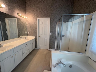 Full bath with double vanity, wallpapered walls, a