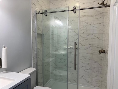 Bathroom featuring vanity, a stall shower, and toi