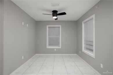 Spare room with baseboards, a ceiling fan, and light marble finish floors