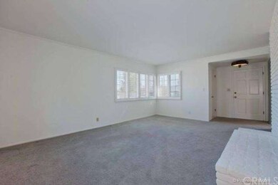 Cozy living room has plantation shutters over Ande