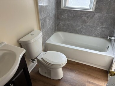 Full bathroom featuring dark wood-style floors, vanity, and a tub to relax in