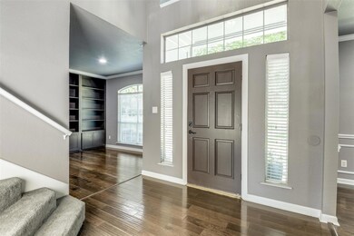 Entrance foyer with dark hardwood / wood-style floors, a towering ceiling, and ornamental molding