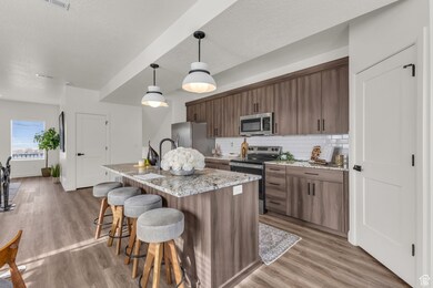 Kitchen with appliances with stainless steel finishes, a breakfast bar area, decorative backsplash, light wood-style floors, and a textured ceiling