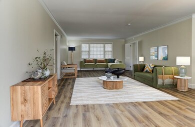 Living area featuring baseboards, wood finished floors, and crown molding virtually staged