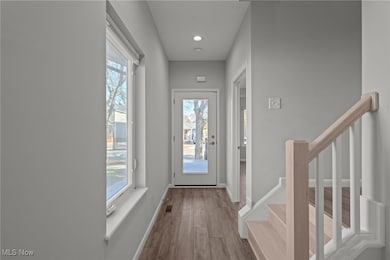 Doorway to outside with stairway, wood finished floors, and recessed lighting