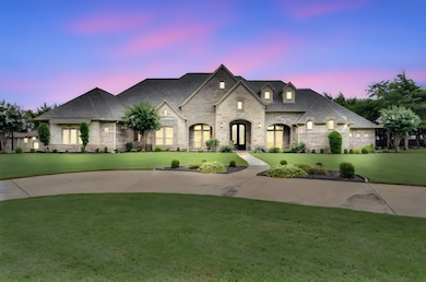 French country home featuring a front yard, stone siding, roof with shingles, and brick siding