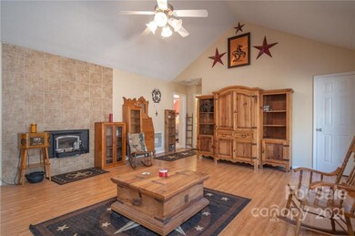 Family Room with vaulted ceiling, ceiling fan and view of tiled wall with wood burning stove. This stove will heat the entire house 