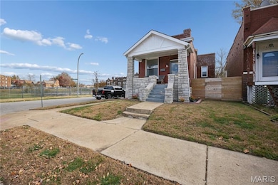 View of front of property featuring a chimney, a porch, and stone siding