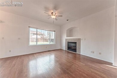 Unfurnished living room featuring baseboards, ceiling fan, a tile fireplace, and wood finished floors