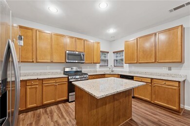 Kitchen featuring appliances with stainless steel finishes, wood finished floors, a sink, recessed lighting, and light stone countertops