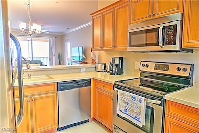 Kitchen with stainless steel appliances, ornamental molding, decorative light fixtures, brown cabinets, and a chandelier