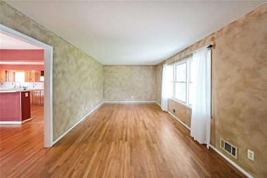 Empty room featuring wood finished floors, healthy amount of natural light, a sink, and baseboards