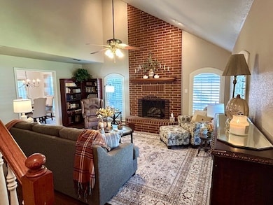 Living area with high vaulted ceiling, a fireplace, a chandelier, and ceiling fan