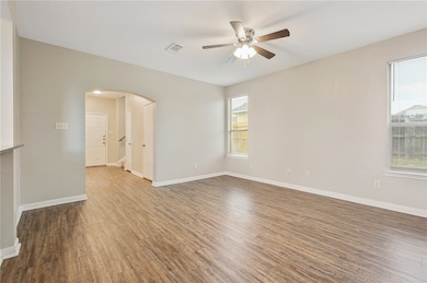 Unfurnished room with wood finished floors, arched walkways, and ceiling fan