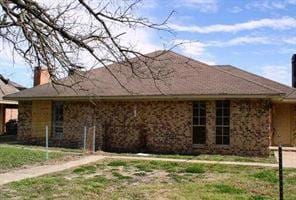View of front of home with a front lawn and a chim