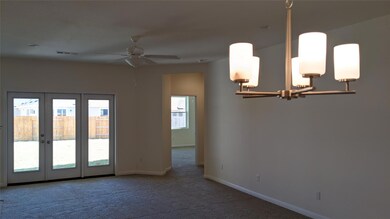 Carpeted spare room with a chandelier, french doo